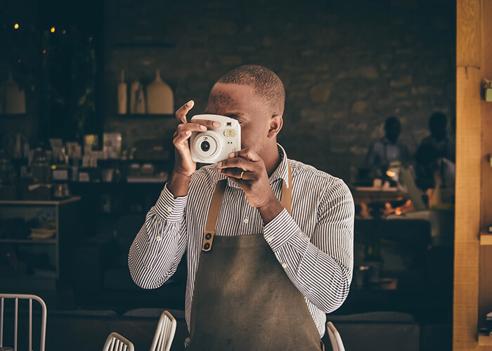 Garçom fotografando no meio do restaurante